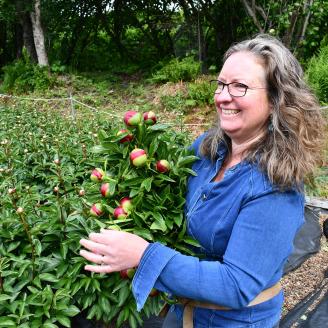 A female farmer holds a bouquet of peony flowers