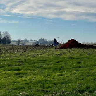 Soil Scientist standing by a spoil pile in a fallow corn field.