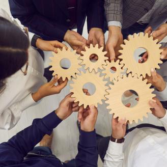 Overhead view on diverse business team people hands holding gear wheels finding working solutions.