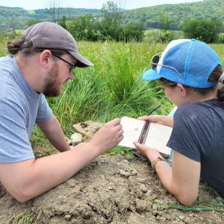 Employees in the field looking at the Field Book for Describing and Sampling Soils.