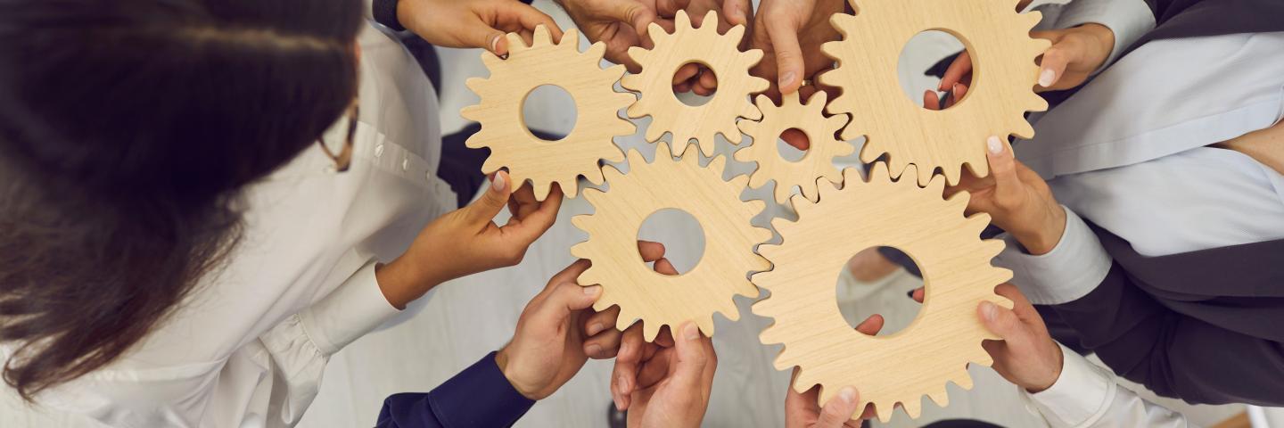 Overhead view on diverse business team people hands holding gear wheels finding working solutions.