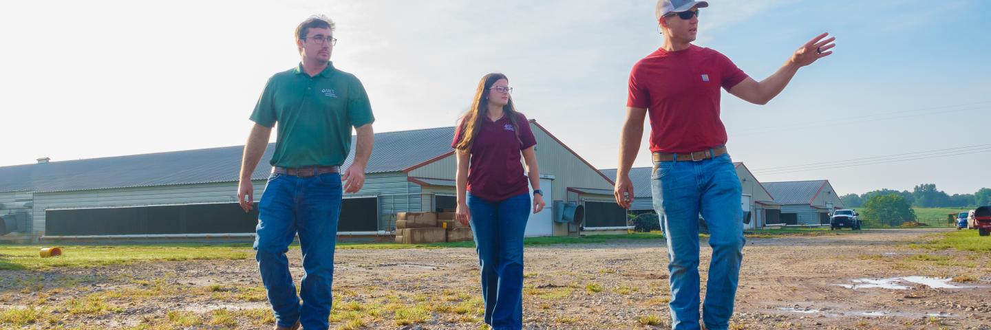 Male poultry producer showing two NRCS field staff his farm