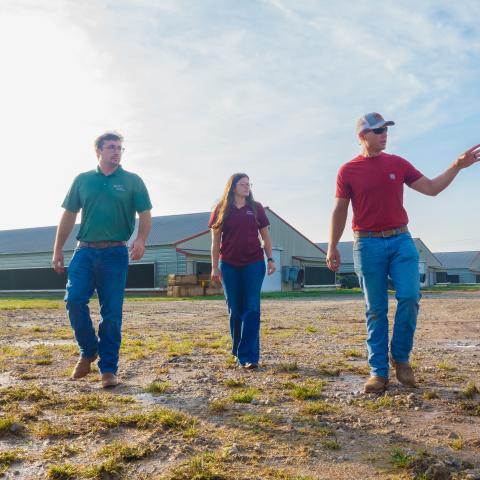 Male poultry producer showing two NRCS field staff his farm