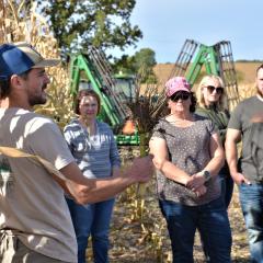 Soil educator showing crowd at a demo farm field day the roots of a corn stalk