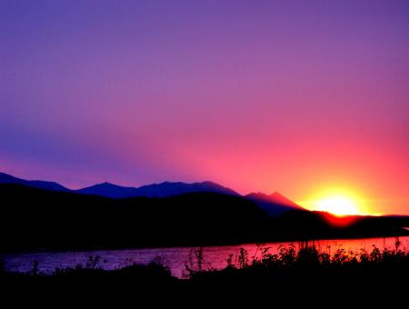 A sunrise over the water with mountains in Alaska.